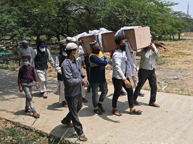 Relatives, friends and graveyard workers carry the body of a coronavirus victim for the burial at a graveyard in New Delhi. Picture: AFP