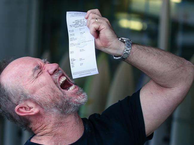 Stuart Surf Design owner Stuart Smith pretending to eat the parking ticket he received from Gold Coast City council. Picture: Glenn Campbell.