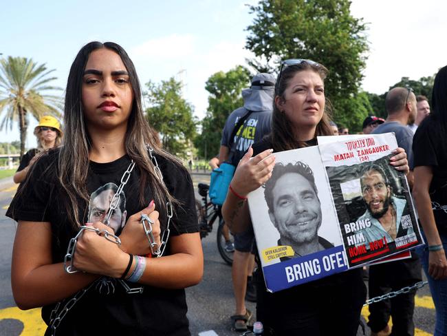 Symbolically chained demonstrators carry pictures of hostages as they block traffic on a main road during an anti-government protest calling for action to secure the release of Israelis held captive since the October 7 attacks by Palestinian militants in the Gaza Strip, in front of the Israeli defence ministry in Tel Aviv on September 13, 2024, amid the ongoing war between Israel and the militant Hamas group. (Photo by JACK GUEZ / AFP)