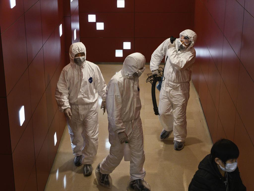 Chinese workers wear protective suits as they work inside a mall on in Beijing. Picture: Kevin Frayer/Getty Images