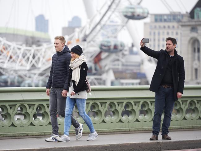 People pose for photographs on Westminster Bridge in central London on March 23, 2017 after the bridge reopened to traffic following its closure during the March 22 terror attack. Picture: AFP