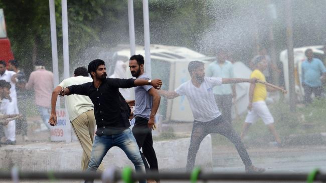 Supporters of Indian religious leader Gurmeet Ram Rahim Singh throw stones at security forces as they are sprayed with a water cannon in Panchkula. Picture: AFP