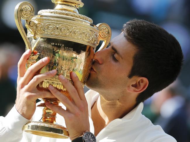 FILE - In this July 6, 2014, file photo, Novak Djokovic of Serbia kisses the trophy after defeating Roger Federer of Switzerland in the men's singles final at the All England Lawn Tennis Championships in Wimbledon, London. Heading into the U.S. Open, Roger Federer, Rafael Nadal, Djokovic and Andy Murray have won 36 of the past 38 Grand Slam titles, a stretch dating to the 2005 French Open. Nowadays, there seems to be a growing sense _ or hope, maybe _ among the best of the rest on the men's tennis tour that the quartet might be more vulnerable than ever. (AP Photo/Ben Curtis, File)