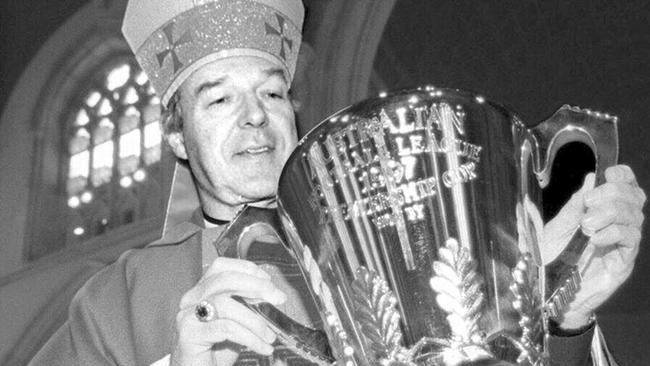 In 1997, Pell — a former footy player — gets to hold the premiership cup at St Patrick's Cathedral. By now he had already abused the boys.