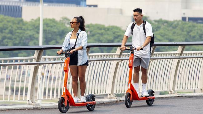 People riding Neuron e-scooters through Brisbane in 2019. A Greens proposal would give residents a vote on whether to ban hireable e-scooters. Picture: AAP/Richard Walker