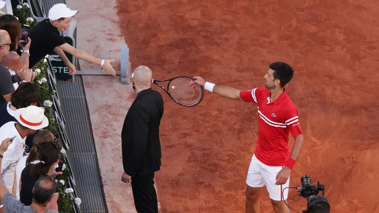 PARIS, FRANCE - JUNE 13: Tournament winner Novak Djokovic of Serbia passes his racquet to a fan as he celebrates after winning his Men's Singles Final match against Stefanos Tsitsipas of Greece during Day Fifteen of the 2021 French Open at Roland Garros on June 13, 2021 in Paris, France. (Photo by Adam Pretty/Getty Images)