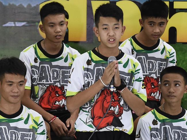 Pornchai Khamluang (C), one of the twelve boys dramatically rescued from deep inside a Thai cave after being trapped for more than a fortnight, speaks during a press conference in Chiang Rai on July 18, 2018, following their discharge from the hospital while coach Ekkapol Chantawong (front-L) and Adul Sam-on (front-R) looks on.  The young footballers and their coach who became trapped deep in a flooded cave complex tried to dig their way out and survived on rainwater for nine days before being found and later rescued. / AFP PHOTO / Lillian SUWANRUMPHA