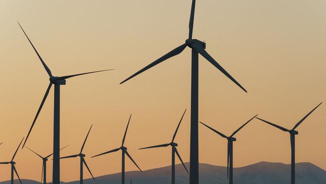 This photograph taken on February 13, 2023 at sunset shows wind turbines in a wind farm in Fuendejalon, with the Moncayo mount in background, Zaragoza province, northern Spain. (Photo by CESAR MANSO / AFP)