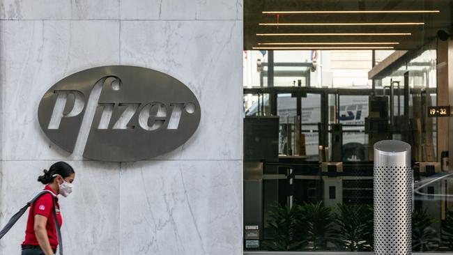 A pedestrian wearing a protective mask walks past Pfizer Inc. headquarters in New York City. Pfizer and German biotechnology firm BioNTech have agreed to supply the U.S. government with 100 million doses of coronavirus vaccine under a $1.95 billion deal. Picture: Getty Images