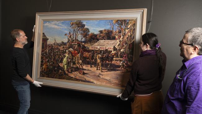 Toowoomba Regional Art Gallery staff (from left) Jayson Althofer, Eloise Tuppurainen-Mason and Sue Lostroh with The Lights of Cobb and Co, 1959 by Ivor Hele, part of the Lionel Lindsay Collection, Thursday, July 18, 2024. Picture: Kevin Farmer