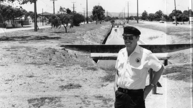 Port Adelaide Historical Society vice president Mr Ron Ritter posing in front of an open drain in middle of Port Road that was the site for a canal from Port Adelaide to Adelaide, at Queenstown, January 1991. Photo: Neon Martin.