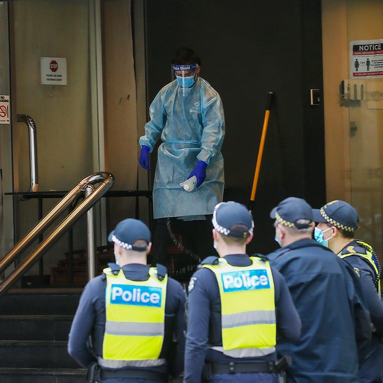 Police watch on as a cleaner disinfects the front of a quarantine hotel. Picture: NCA NewsWire / Ian Currie