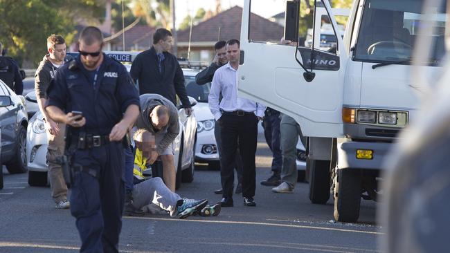 Police help the driver to his feet after placing handcuffs on him.