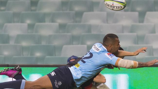 Waratahs star Kurtley Beale dives for a ball against a backdrop of empty seats on Saturday night.