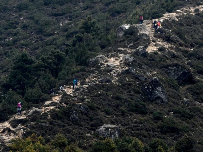 Trekkers and porters walk along a path at the base of Mount Everest. Picture: PRAKASH MATHEMA / AFP