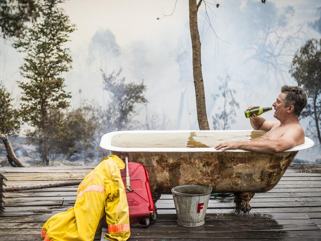 Simon Crisp takes a well earned bath and a beer only minutes after saving his property with the help of the CFA from the bushfire. Picture: Jason Edwards