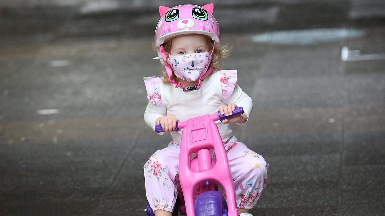 Elodie, a young resident, wears a mask as she rides her bike. (Photo by Jono Searle/Getty Images)