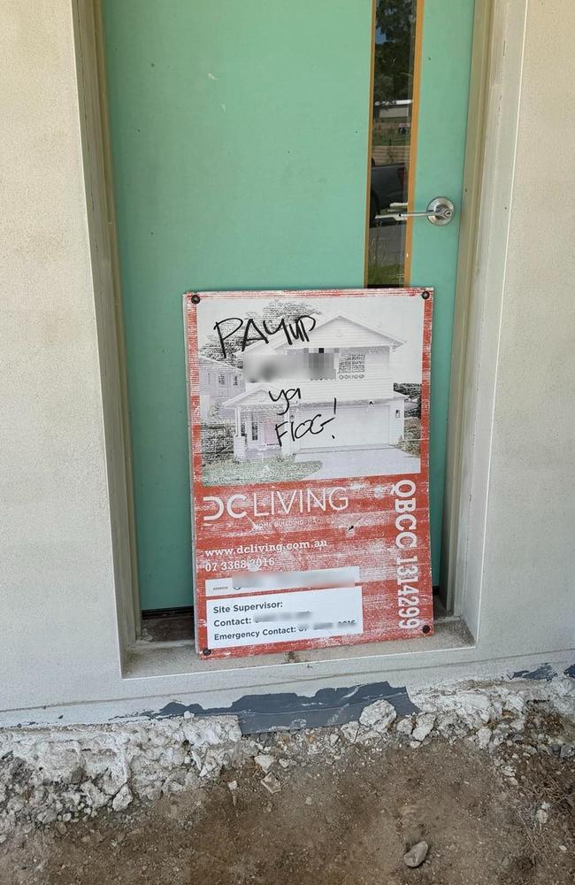 A tradie leaves a sign that reads “pay up ya flog” on a site belonging to collapsed builder DC Living.