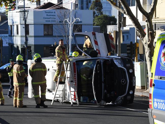 Firefighters use a step ladder to reach the passenger side door. Picture: AAP/James Ross