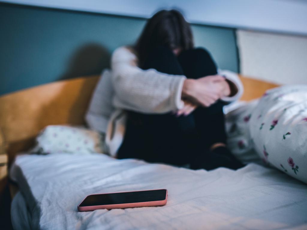 teen with a phone in a bed