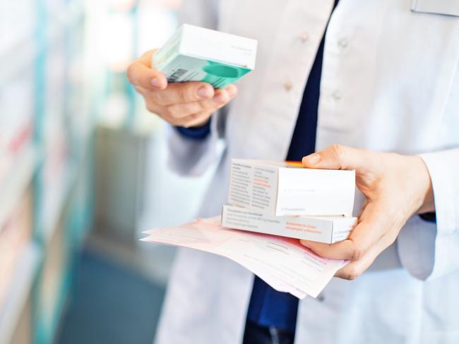 Closeup of pharmacist's hands taking medicines from shelf at the pharmacy
