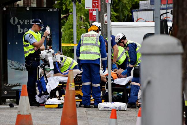 Police and emergency rescue workers assist paramedics as they treat a victim at the crash site. Picture: Adam Yip