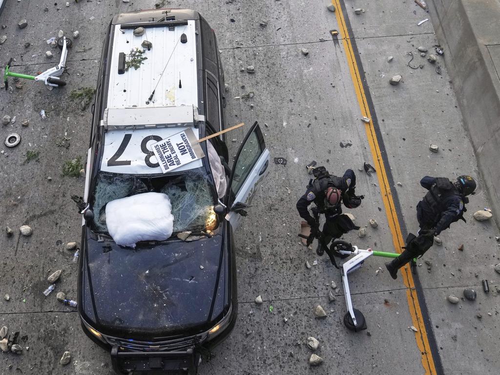California Highway Patrol officers try to dodge rocks being thrown near the Metropolitan Detention Centre in downtown Los Angeles. Picture: AP
