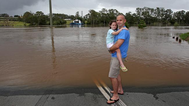 John Vaisutis with daughter Zoe, 6, survey the flooded Brisbane River at the Moggill Ferry. A developer who wants to build on a nearby floodprone site at Weekes Rd must install a warning siren, a court has ruled. Picture: Tim Marsden