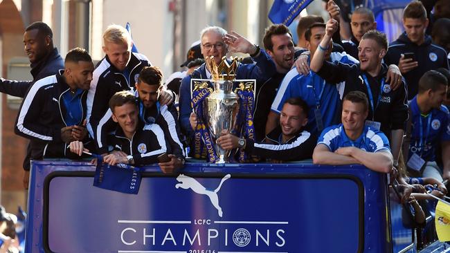 Leicester City's Italian manager Claudio Ranieri (C) holds the Premier league trophy as the Leicester City team take part in an open-top bus parade through Leicester to celebrate winning the Premier League title on May 16, 2016. / AFP PHOTO / PAUL ELLIS