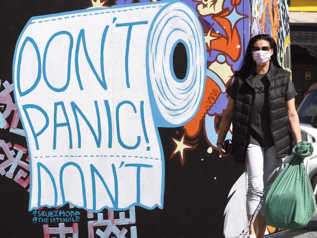 A face mask-clad woman passes a mural in the Melbourne suburb of Prahran on September 10, 2020. - Melbourne is experiencing long harsh lockdown rules as it battles a second wave of the Covid-19 coronavirus. (Photo by William WEST / AFP)