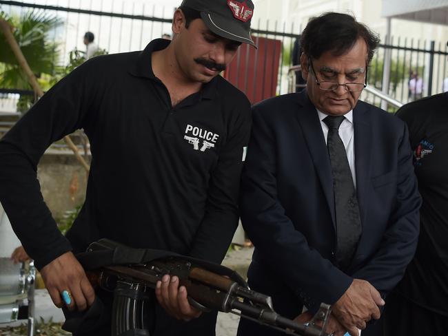 A policeman escorts Asia Bibi’s lawyer Saiful-Mulook. Photo: Aamir Qureshi/AFP