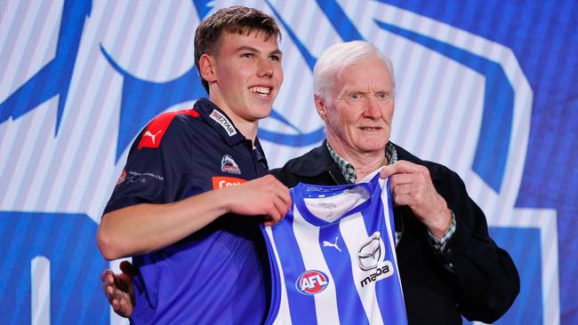 Finn O’Sullivan is presented with his North Melbourne jumper by dual Brownlow Medallist Keith Greig. Picture: Dylan Burns