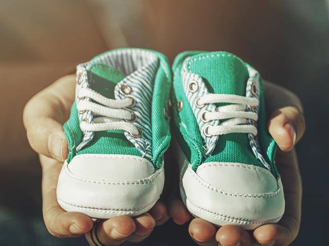 Future parents holding a pair of little shoes