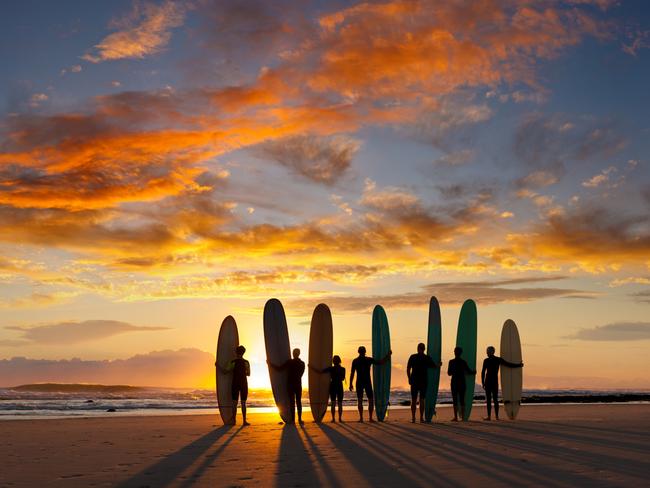 ESCAPE: A group of young and old malibu (longboard) surfers about to go surfing at sunrise. Picture: Istock