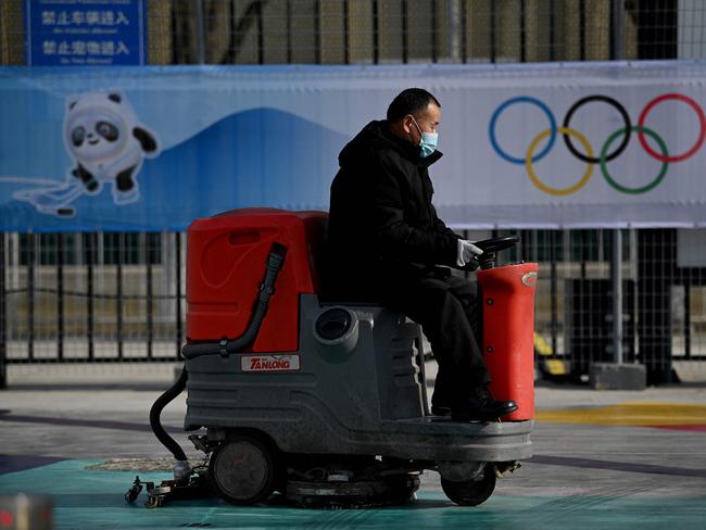 A worker sweeps the ground in front of a picture of Bing Dwen Dwen, a mascot of the 2022 Beijing Winter Olympic Games in Beijing. Picture: Noel Celis / AFP