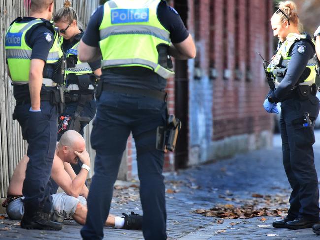 Police speak to a drug-affected man near the injecting room. Picture: Tony Gough