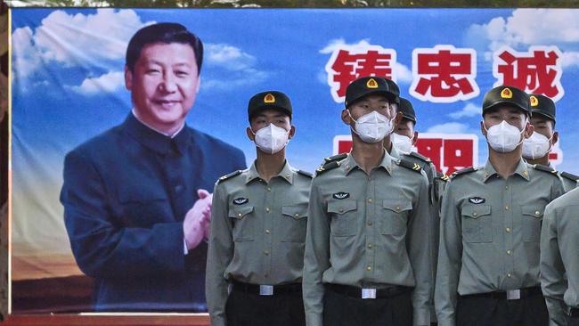 Soldiers of the People's Liberation Army's Honour Guard Battalion wear protective masks as they stand at attention in front of photo of China's president Xi Jinping at their barracks outside the Forbidden City, near Tiananmen Square. Picture: Getty Images