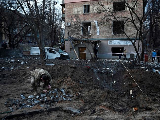 A serviceman collects fragments of missile in a crater left by a Russian strike in front of a residential building in the Ukrainian capita Kyiv on December 31. Picture: AFP