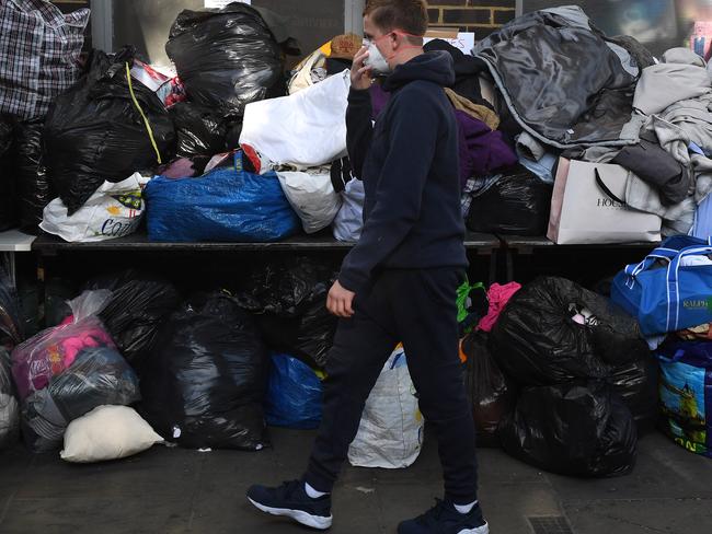 A boy wears a face mask as he walks past donated clothing, water and food. Picture: Chris J Ratcliffe/Getty Images