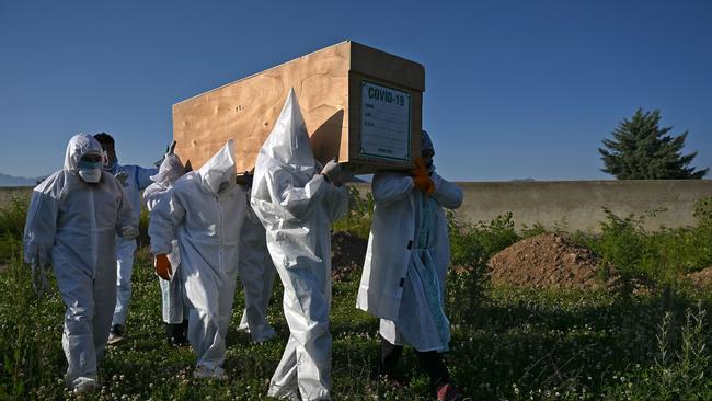 Relatives wearing PPE carry the coffin of a woman who died from COVID-19 through a graveyard in in Srinagar on May 21.