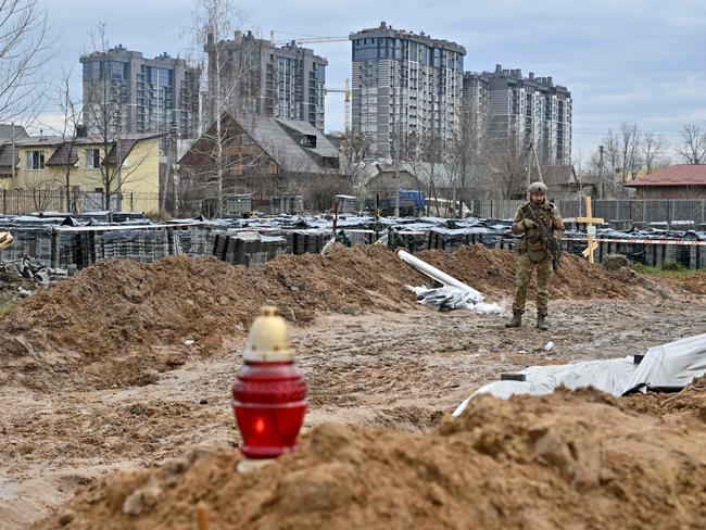 A Ukrainian serviceman stands guard near a mass grave in Bucha, near Kyiv. Picture: AFP