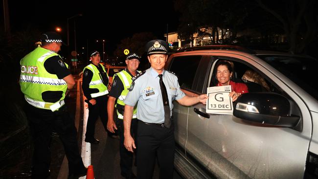 Queensland Police Superintendent Mark Wheeler takes back a QLD Border pass and welcomes Wendy Van den Akker as the first vehicle back into the state after border restrictions were lifted at 1am. Picture: Scott Powick