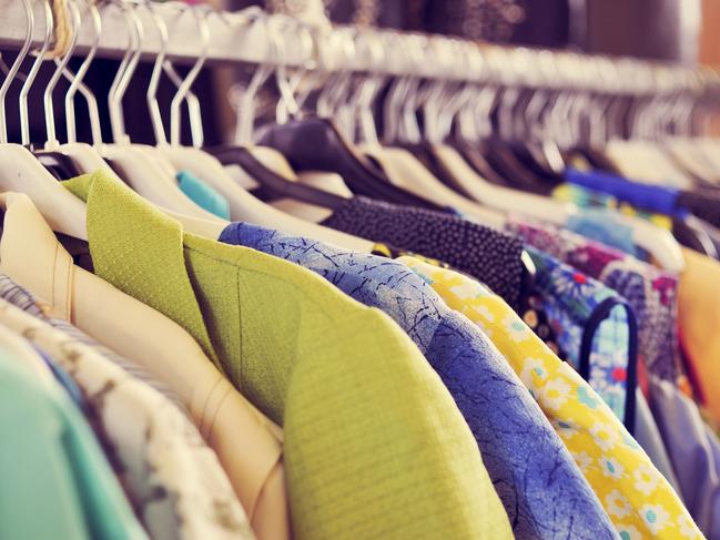 some used clothes hanging on a rack in a flea market