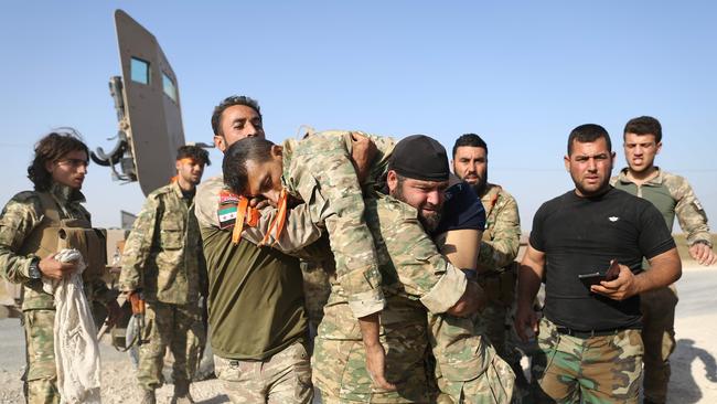 Turkish-backed Syrian fighters evacuate a wounded comrade near the border town of Ras al-Ain. Picture: AFP.