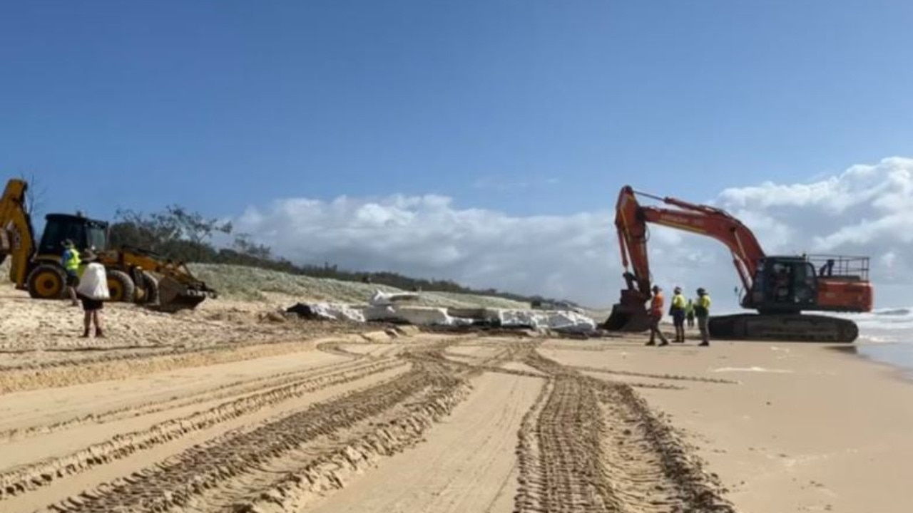 An excavator and a dozer are being used to remove large pontoons that were washed up on Noosa beaches during recent flooding. Picture: Sharyn Kerrigan