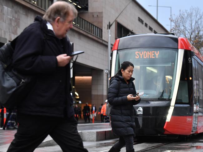 Morning commuters walk past a tram on its way to Circular Quay during it's testing phase. Picture: AAP Image/Dean Lewins