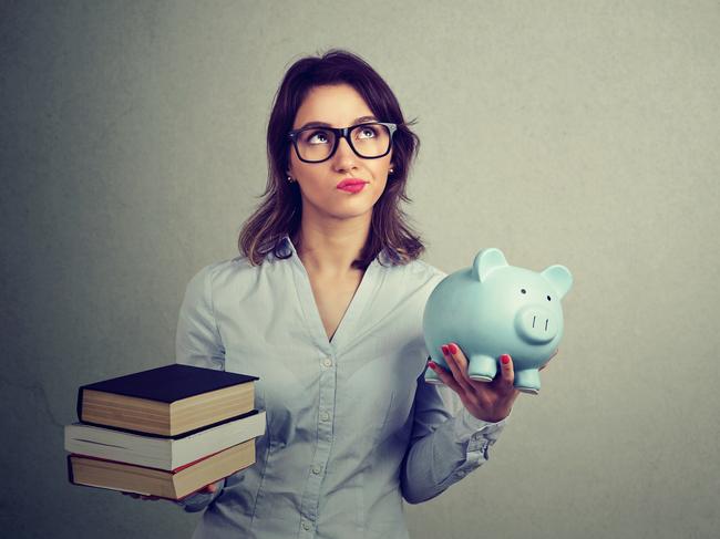 Student loan concept. Young woman with pile of books and piggy bank full of debt rethinking future career path