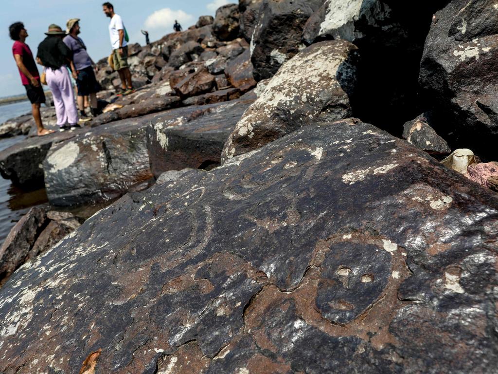 Tourists gather to look at the ancient rock carvings that reappeared in the region of the Pontos das Lajes archaeological site due to the severe drought affecting the region's rivers on the banks of the Negro River in Manaus in northern Brazil. Picture: Michael Dantas/AFP