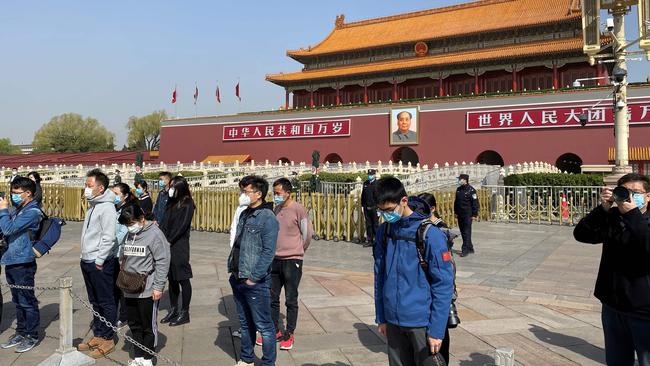 People wearing face masks mourn patients and medical staff killed by coronavirus during a nationwide three minutes silence along a business street in Beijing on April 4, 2020. – China came to a standstill to mourn patients and medical staff killed by the coronavirus, with the world's most populous country observing a nationwide three-minute silence. (Photo by LEO RAMIREZ / AFP)