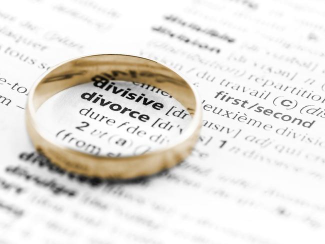 Divorce term highlighted in selective focus from dictionary book, or from law document. Concept of family separation with a wedding ring.